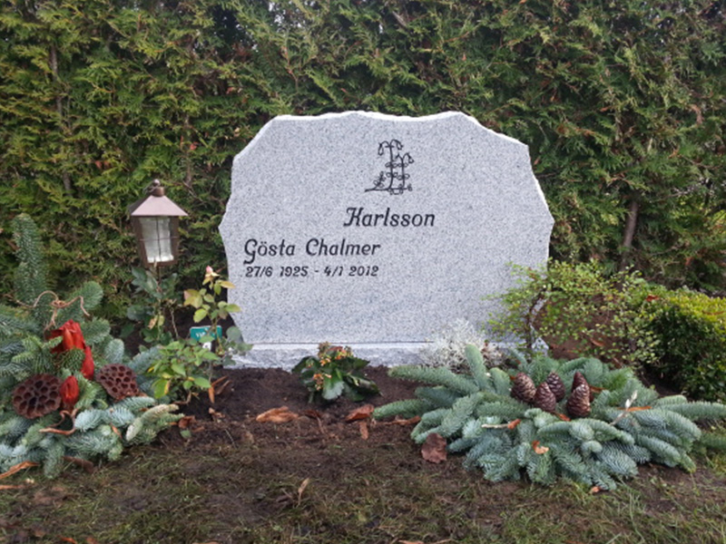 E049 i polerad ljusgrå granit. Råarbetade sidytor och försänkt svartmålad gravyr.