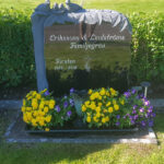 E066 i svart granit monterad på befintlig gravram. Text och dekor är försänkt målad antikvit.