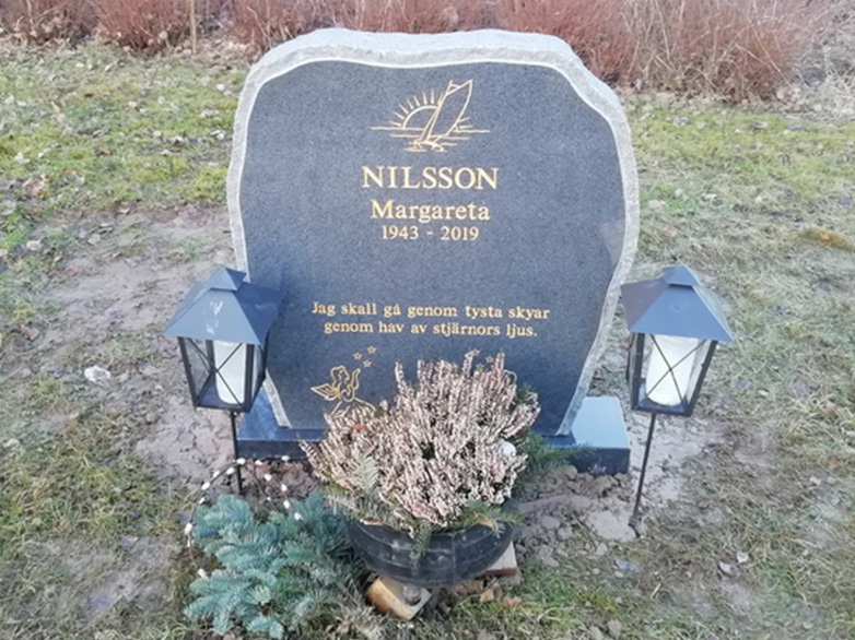 E016 i mörkgrå granit och förgylld gravyr. Polerad fram med råarbetat kantslag och sidoytor.