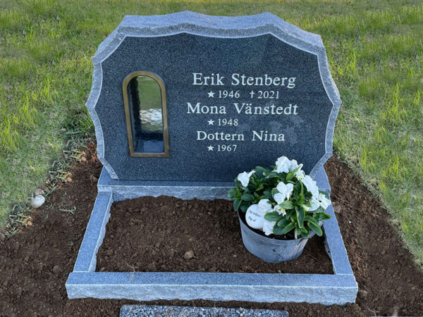 E049 i mörkgrå granit. Blomlist med polerad ovansida, lyktram i brons, gravyr försänkt målad antikvit.