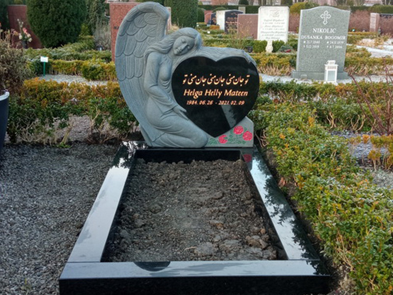 E082 i svart granit. Polerad gravram, försänkt förgylld text, tecken utöver latinska alfabetet, försänkt dekor i färger utöver standardutbud.