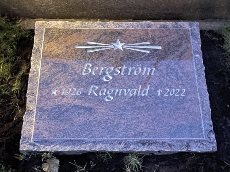 E086 i polerad rödflammig granit med råarbetad kant och sidytor. Försänkt antikvit gravyr.
