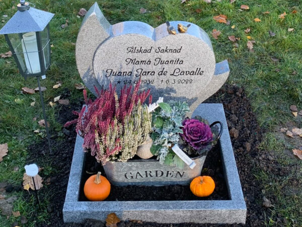 E080 i ljusgrå granit, anpassade mått. Polerad blomlist, bronssparvar och försänkt svartmålad gravyr.