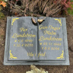 E063 in polished black granite. Recessed, gold-painted engraving and bronze sparrows at the top.