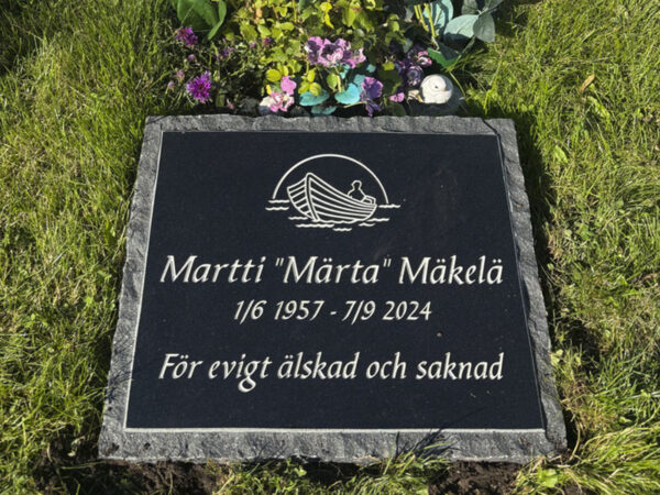 E086 i svart polerad granit med råarbetad kant och sidor. Snedsågad, försänkt antikvit gravyr.