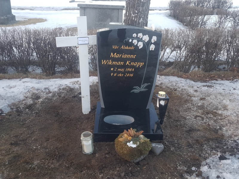 E006 i polerad svart granit med mattslipade detaljer. Planteringssockel och intarsiadekor, texten försänkt och förgylld.