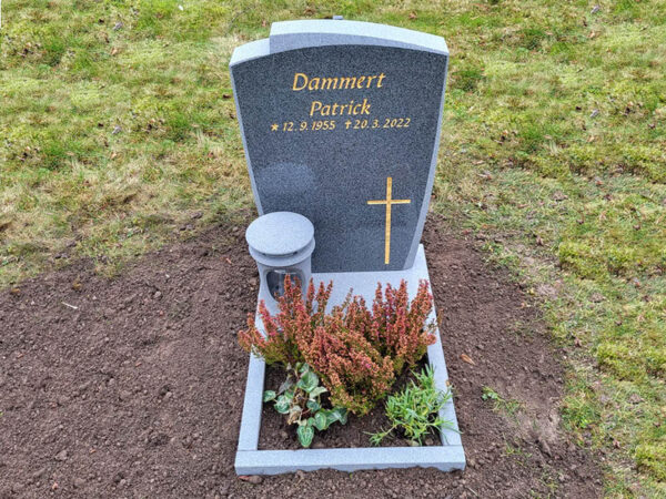 E006 i mörkgrå granit, polerad med mattslipade detaljer. Mattslipad blomlist och granitlykta samt försänkt förgylld gravyr.