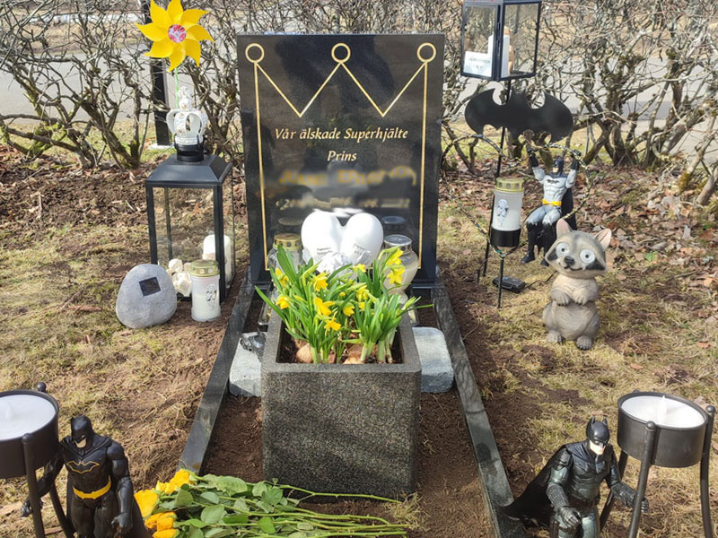 EN102 i polerad svart granit. Gravyr försänkt förgylld, egna dekormotiv samt extra djup blomlist.