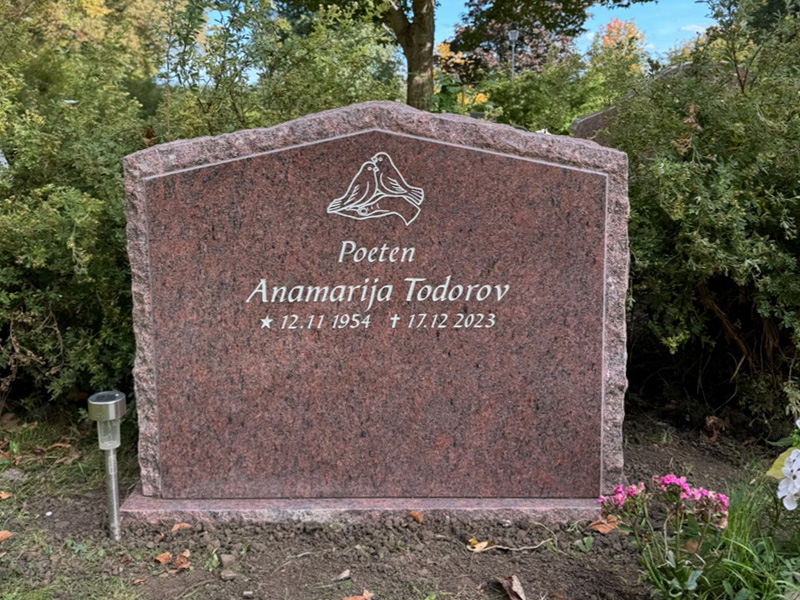 EN110 i finslipad röd Vångagranit, med råarbetat kantslag och sidytor. Försänkt antikvit gravyr.