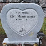 EN104 in grey Kuru granite. Engraving in the fine-chiseled heart is deep sandblasted and lacquered; the rings are recessed and gilded on the matte-polished surface.