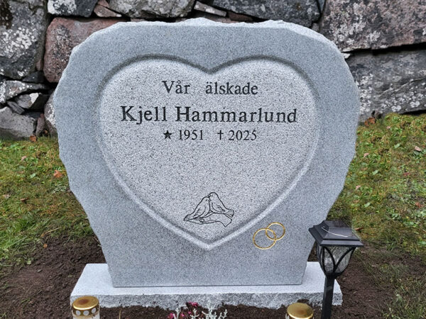 EN104 in grey Kuru granite. Engraving in the fine-chiseled heart is deep sandblasted and lacquered; the rings are recessed and gilded on the matte-polished surface.