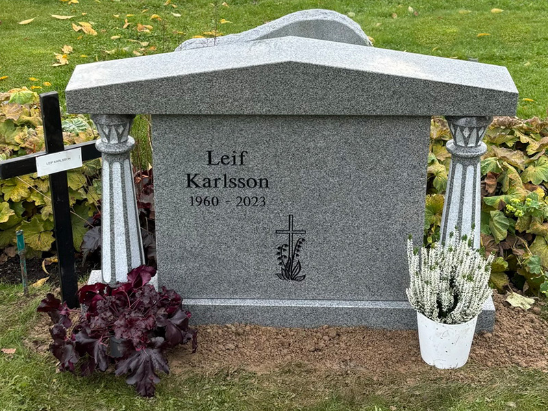 EN053 i polerad Kurugranit med skulpterade detaljer på pelarna. Försänkt svartmålad gravyr.