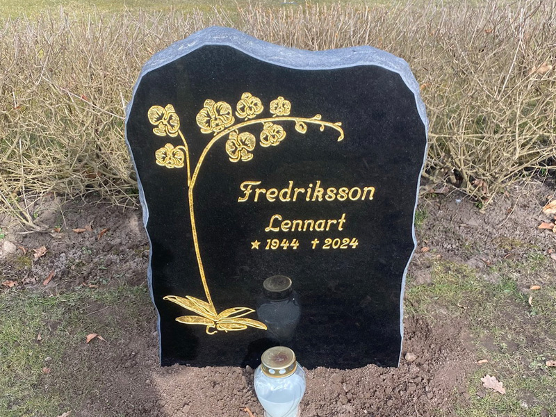 EN015 i polerad svart diabas med råarbetade sidytor. Försänkt förgylld gravyr, stor mängd bladguld.